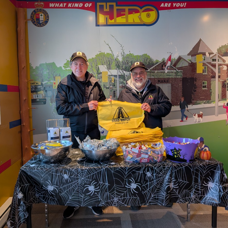 Marty Paulin distributing Road Watch bags and candy behind a table at Halloween in the Safety Village